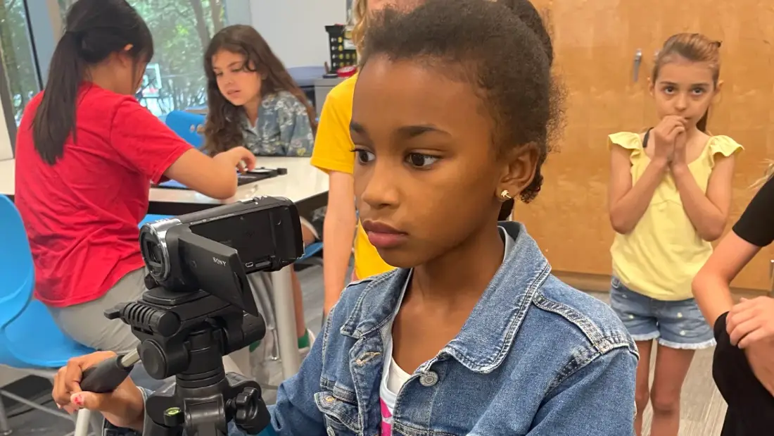 A camper framing a shot on a tripod at an after-school session