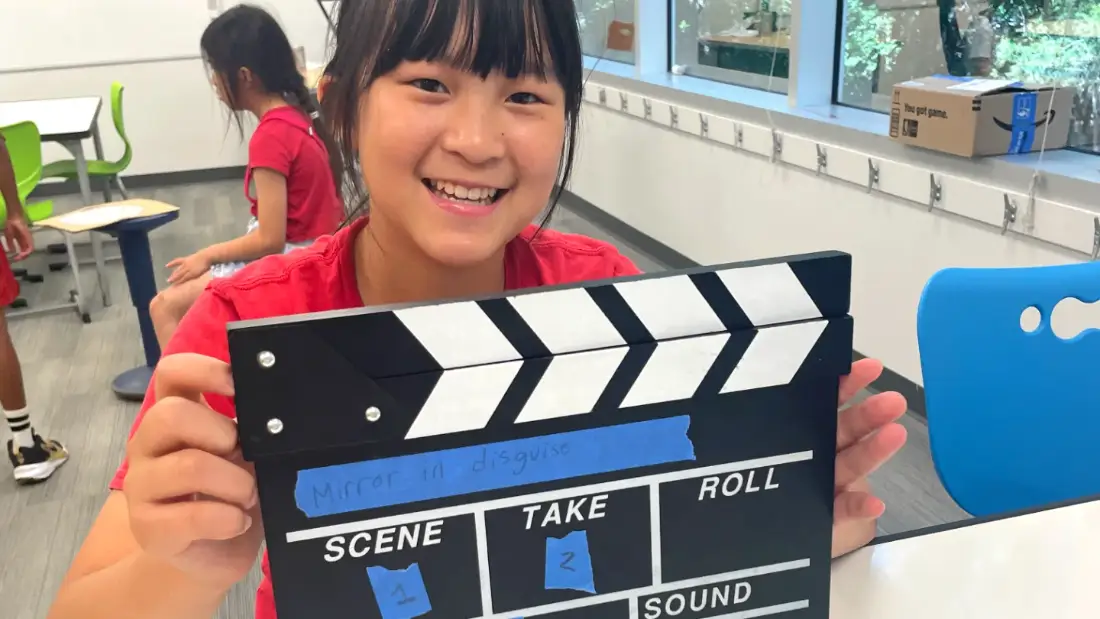 A camper holding a slate for her film Mirror in Disguise