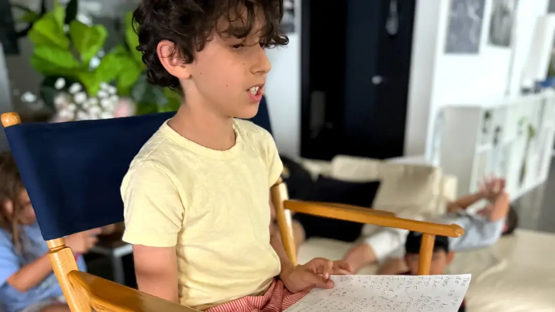 A camper reading his script aloud from the director's chair