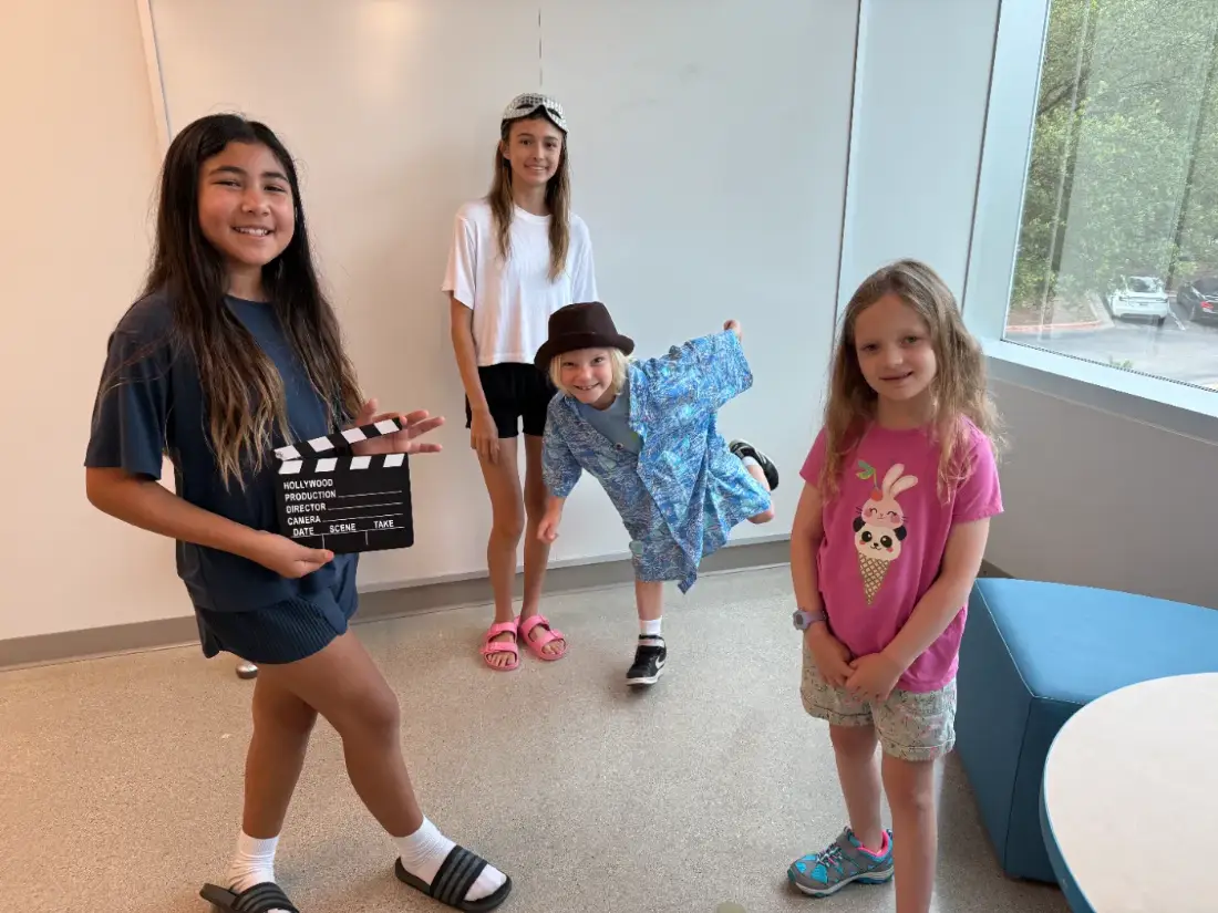 Four campers with a slate and costumes at an after-school session