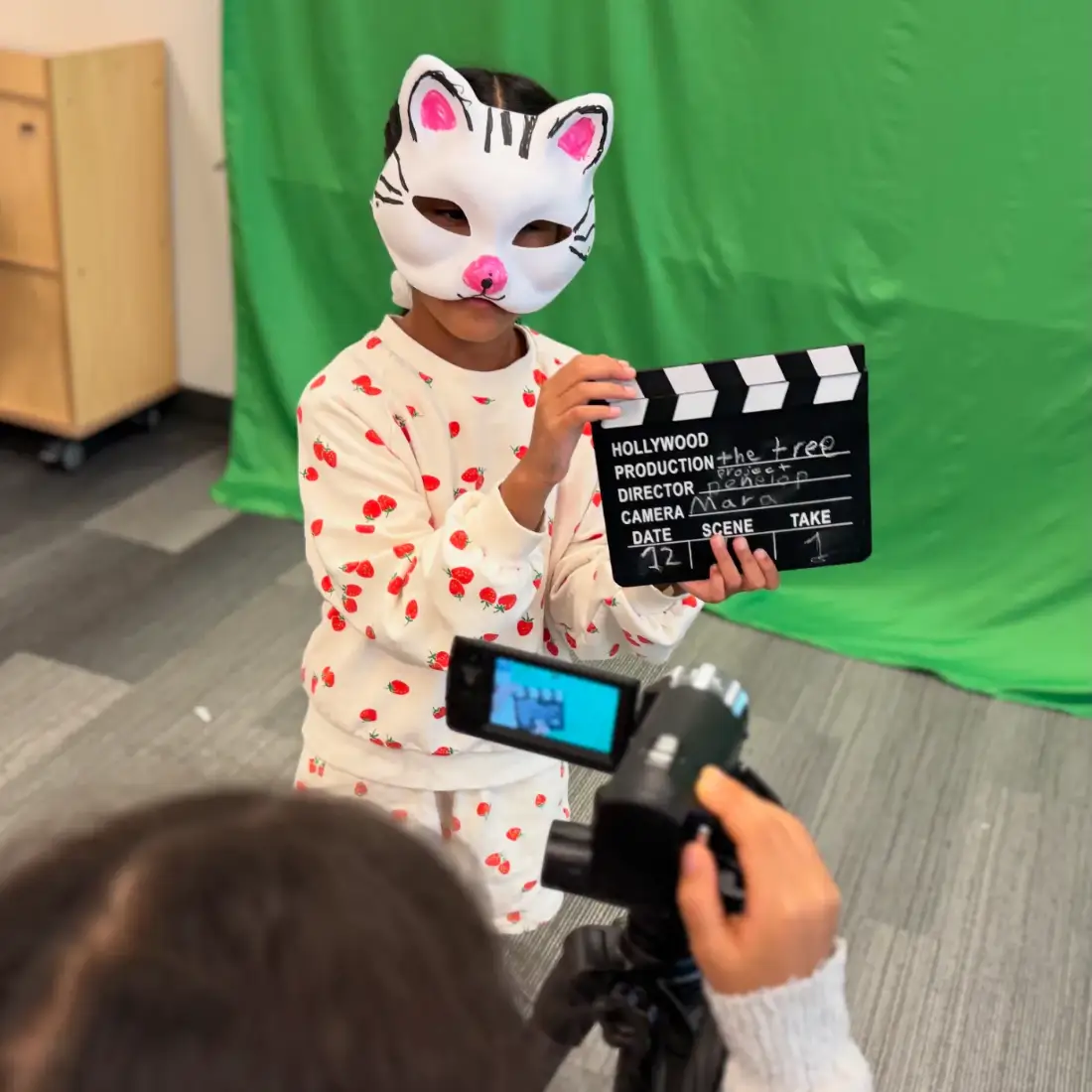 A camper slating take one of her film on the green screen stage