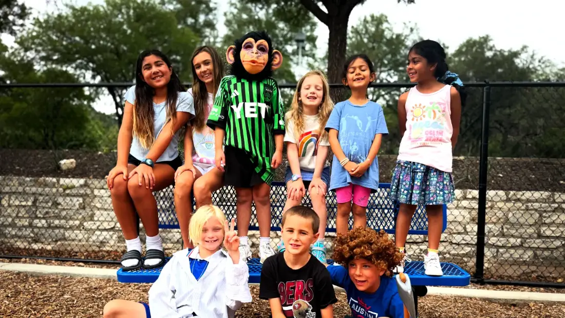 A camp cast in costume outside between setups