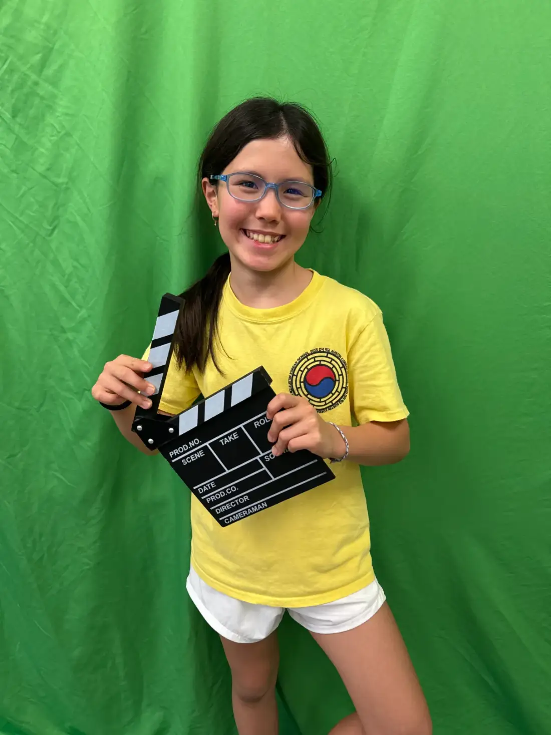 A camper holding the slate on the green screen stage