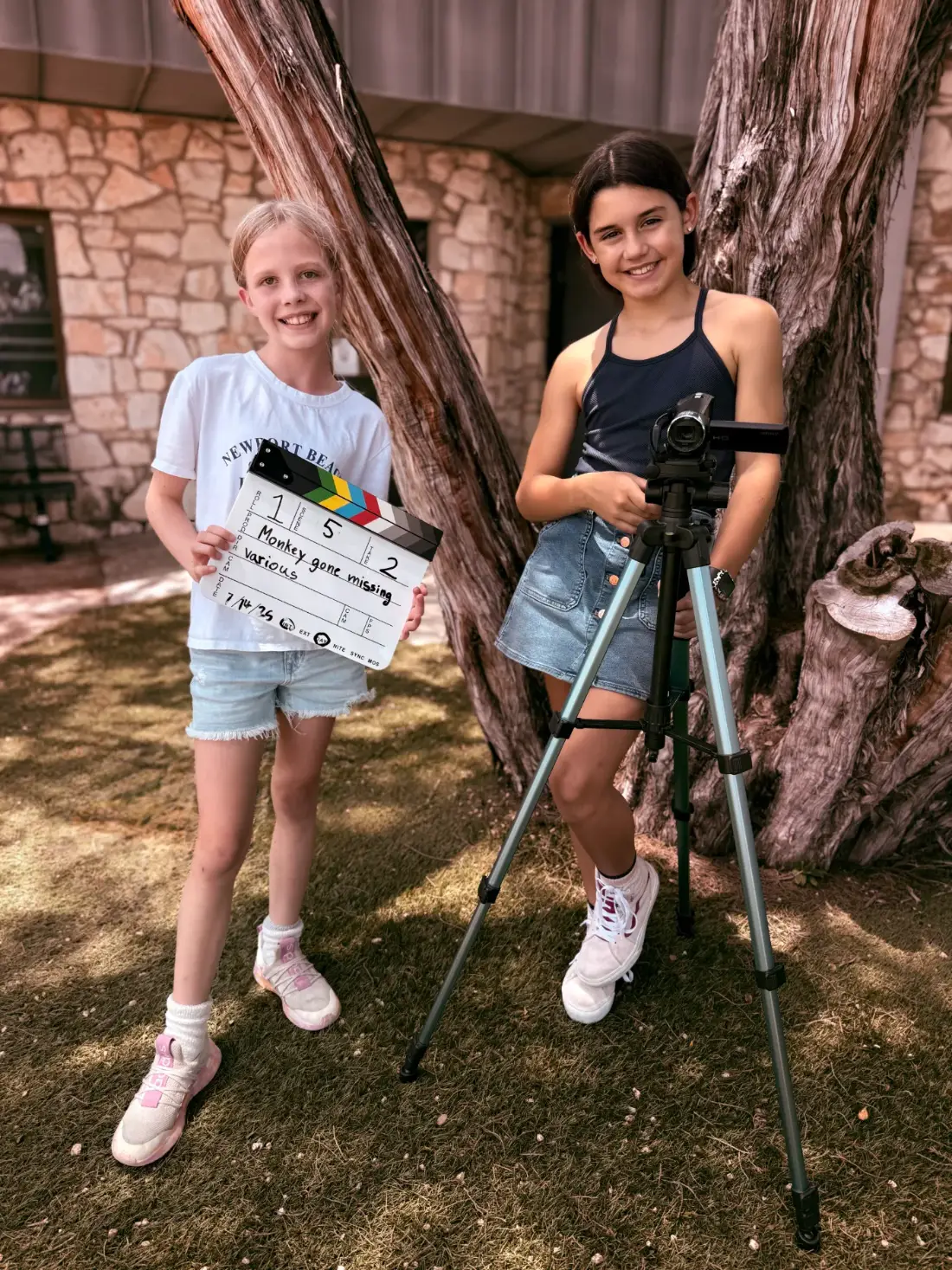 Two campers with a slate and a tripod outside, ready for take two