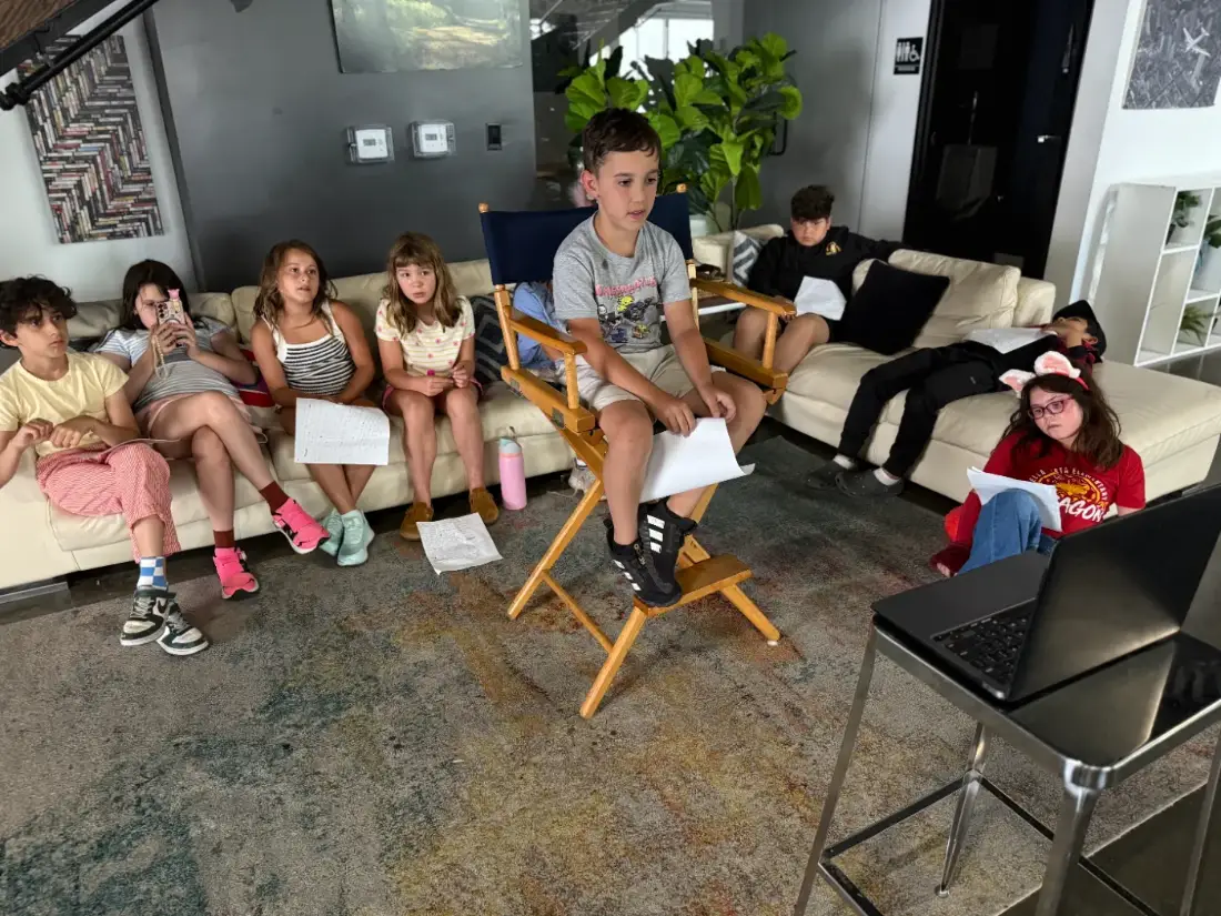A Sunday class listening as a camper reads his pages from the director’s chair