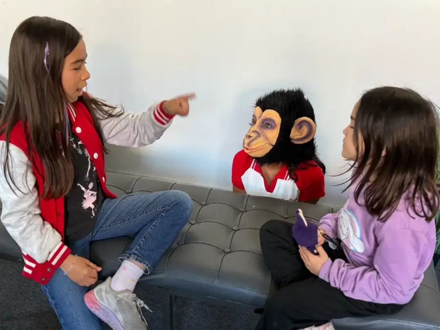 Three young actors rehearsing a scene, one of them in a monkey mask