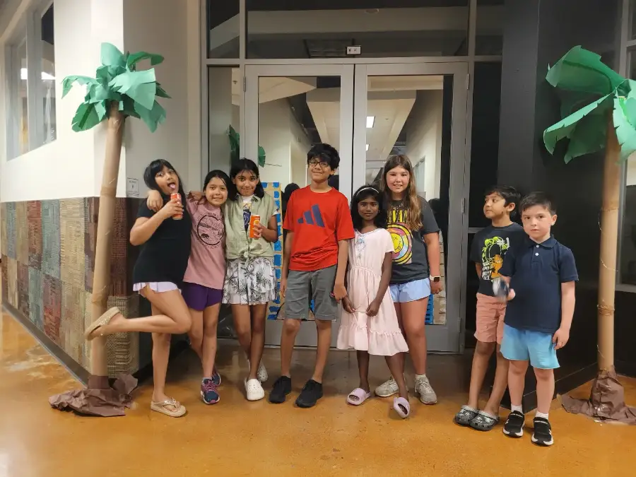 A camp crew posing under the paper palm trees they built for their set