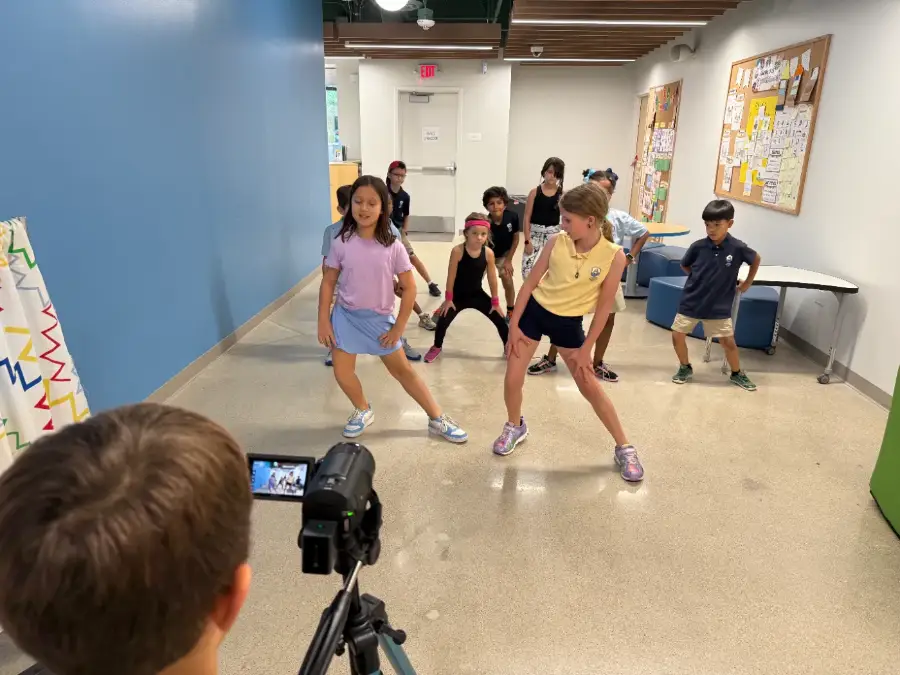 A camper filming two actors mid-scene from behind the tripod