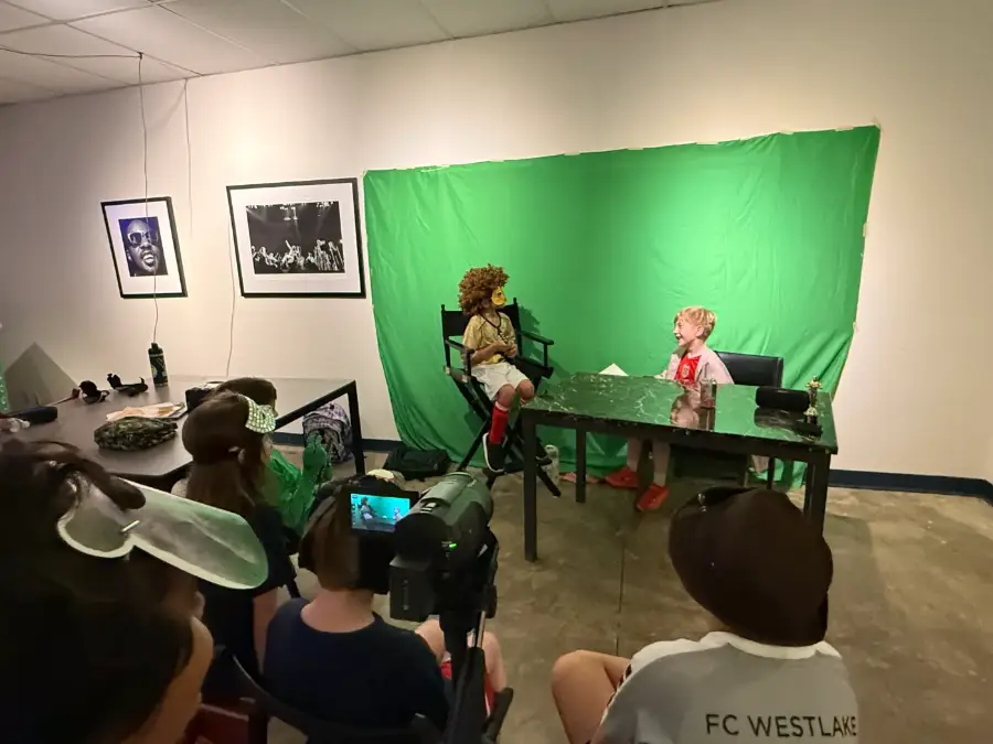 A green-screen talk-show scene in progress, the crew watching the monitor