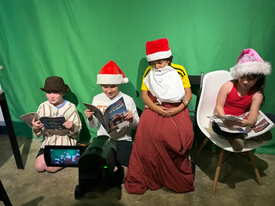 Four young actors in costume shooting a scene on the green screen