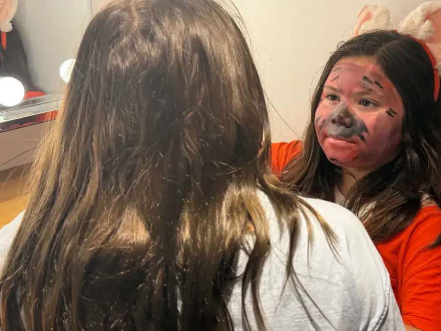 A camper in full character make-up checking herself in the mirror